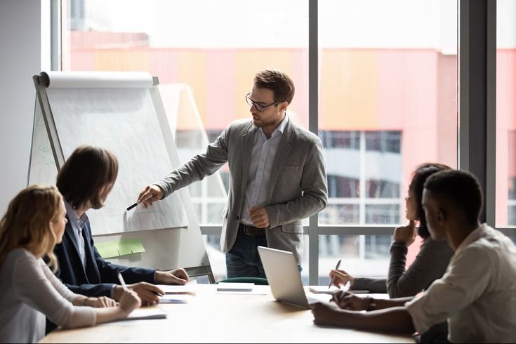A man delivers a presentation to his colleagues, focusing on strategies to boost brand awareness for Digitixel Marketing.
