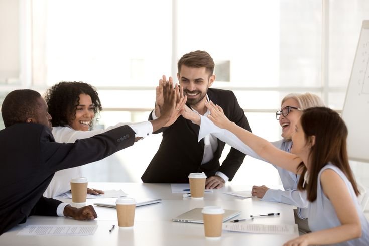 . Two business people exchanging a high five, representing teamwork and success in a sales environment.